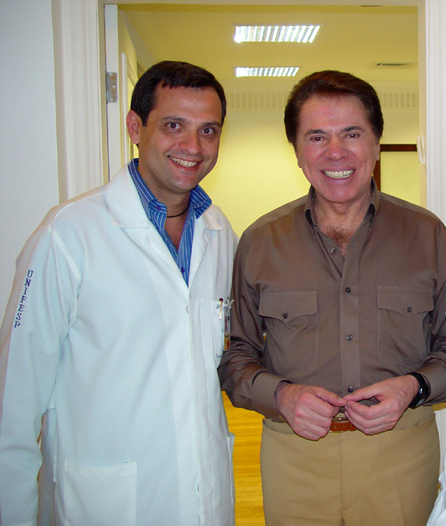 Duas pessoas posando lado a lado em uma sala.